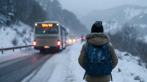 Bambino con zaino cammina su strada innevata dopo essere stato fatto scendere dal bus