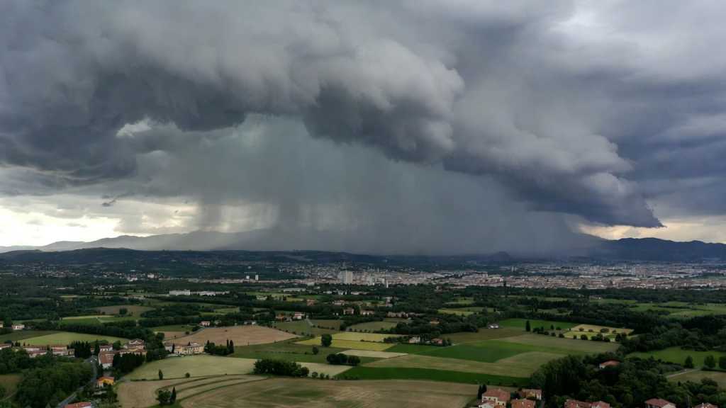 Tempesta con fulmini e grandine su campi italiani con vento forte e cielo scuro