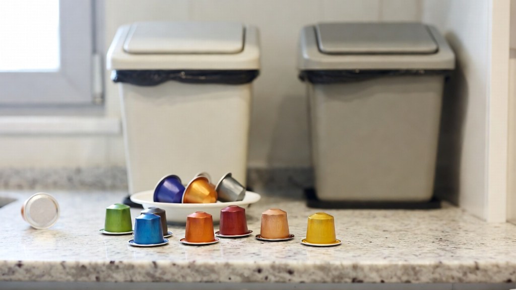 Capsule di caffè usate accanto ai contenitori per la raccolta differenziata
