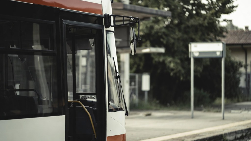 Autobus sostitutivo fermo sul piazzale di una stazione ferroviaria con le porte aperte