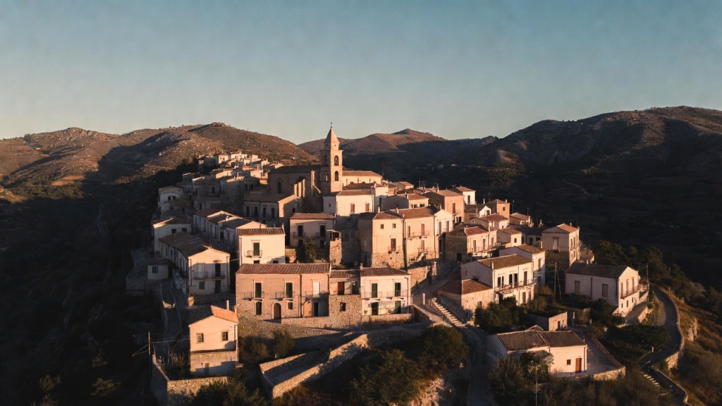 Borgo collinare siciliano con case in pietra e campanile barocco al tramonto, per l’elenco dei Borghi più belli d’Italia in Sicilia