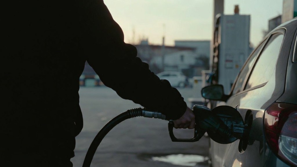 Un lavoratore fa rifornimento all'alba a un distributore self service prima di andare al lavoro