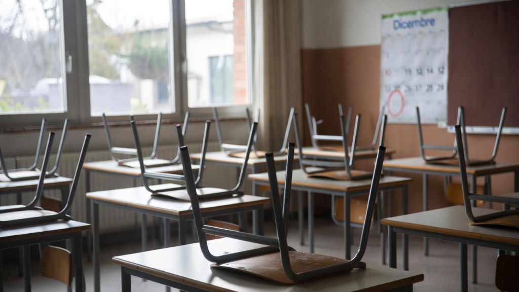 Aula scolastica vuota con sedie sui banchi e calendario di dicembre alla parete per il ponte dell’Immacolata