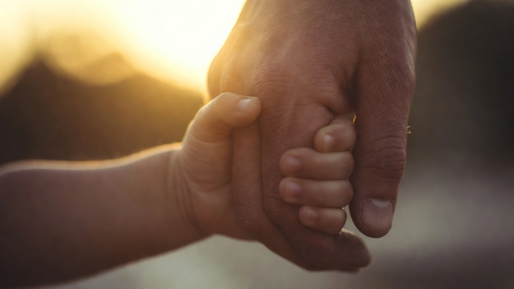 Silhouette di un adulto che stringe a sé un bambino sospesi controluce al tramonto, immagine simbolica per la storia del padre di Pordenone